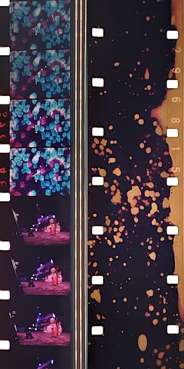 A color photo of two side-by-side strips of 16mm film. The one on the left has frames with colorful abstract forms. The one on the right is negative film that appears to have been contact exposed while splashes with liquid.