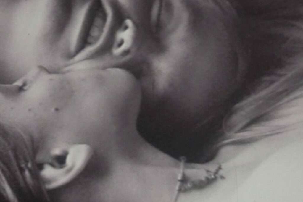 A black and white close-up image of two white women lying side-by-side, cheek-to-cheek.