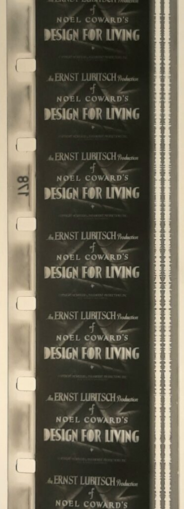 A color photo of a strip of 16mm film. Each frame displays the black and white title card to Ernst Lubitsch's Design for Living.